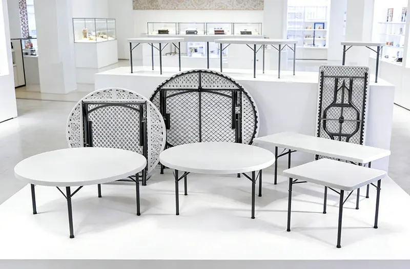 Various white plastic folding tables are placed in the exhibition hall